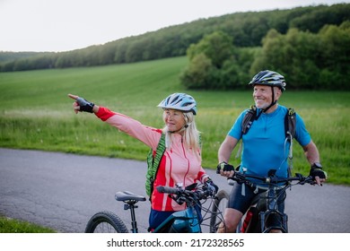 Active senior couple riding electric bicycles on road at summer park, healthy lifestyle concept. - Shutterstock ID 2172328565