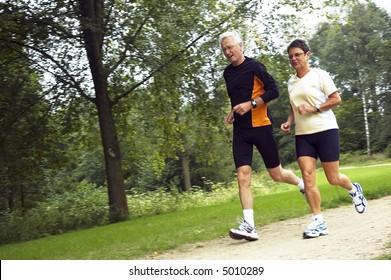 Active Senior Couple Running In The Woods.