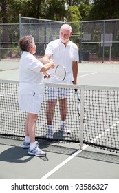 Active Senior Couple Shakes Hands Over The Tennis Net.