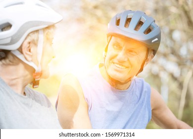 Active senior couple walking while talking in park with yellow lens flare - Shutterstock ID 1569971314