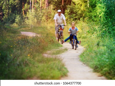 Active Senior With Grandkids Riding Bikes In Nature