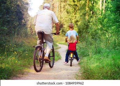 Active Senior With Grandkids Riding Bikes In Nature