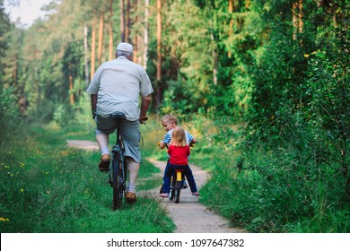 Active Senior With Grandkids Riding Bikes In Nature