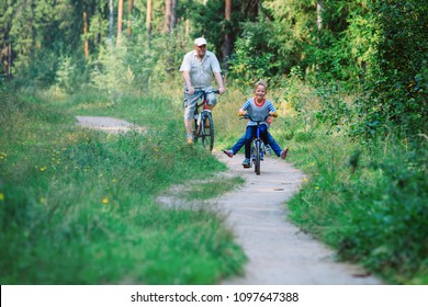 Active Senior With Grandkids Riding Bikes In Nature