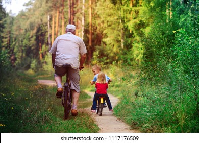 Active Senior With Grandkids Riding Bikes In Nature