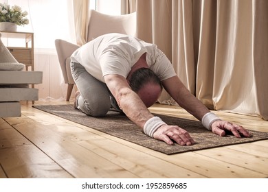 Active Senior Man Doing The Child Pose While Practicing Yoga On A Mat