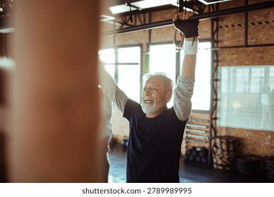 Active senior man doing pull-ups in gym