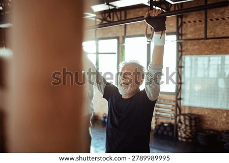 Active senior man doing pull-ups in gym