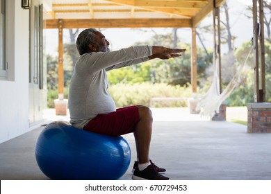 Active senior man exercising on exercise ball in the porch - Powered by Shutterstock