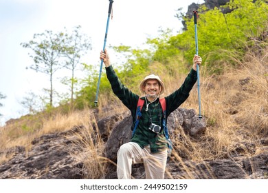 active senior man in hiking clothes,standing on the hill,freedom emotion,right hands holding trekking poles raising up,concept of elderly people lifestyle activity,active,adventure,exploring in nature - Powered by Shutterstock