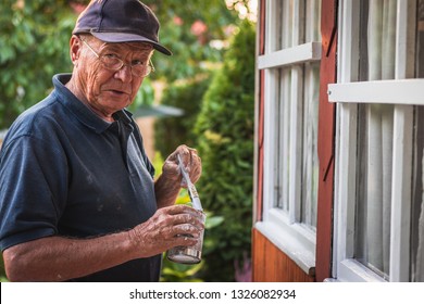 Active Senior Man Painting House Exterior. Old Craftsperson Repairing Window Frame