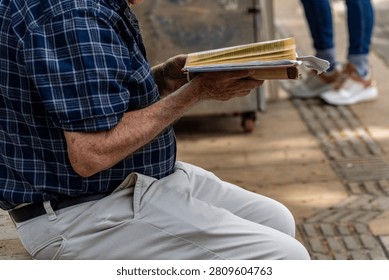 Active Senior man Reading an Open Book Contemplatively on a Wooden Park Bench in a Lush Green Park, Lifestyle, Contemplation, Education, Retirement, Active Aging