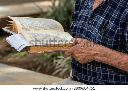 Active Senior man Reading an Open Book Contemplatively on a Wooden Park Bench in a Lush Green Park, Lifestyle, Contemplation, Education, Retirement, Active Aging