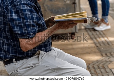 Active Senior man Reading an Open Book Contemplatively on a Wooden Park Bench in a Lush Green Park, Lifestyle, Contemplation, Education, Retirement, Active Aging