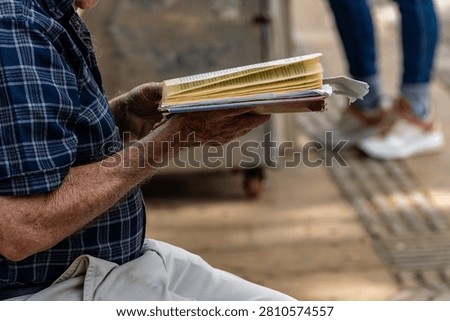 Active Senior man Reading an Open Book Contemplatively on a Wooden Park Bench in a Lush Green Park, Lifestyle, Contemplation, Education, Retirement, Active Aging