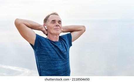 Active senior man is relaxing outside. Elderly man is doing spotr exercising early morning by sea beach. Healthy retirement lifestyle. - Powered by Shutterstock