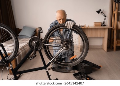 Active senior man repairing bicycle at home. cycling leisure. Retired male home mechanic with equipment for bike maintenance fixing wheel with wrench. Copy space
