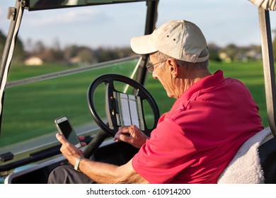 Active senior man sitting in golf cart using a smartphone mobile device. - Powered by Shutterstock