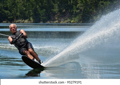 An active senior man water skier in his 70's preforming water skiing sport skills on lake in New Zealand. Real People. Copy space 