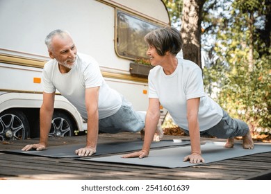 Active senior old elderly caucasian athletes grandparents doing sporty activity on fitness mats, slimming together while on a trip in trailer camper van caravanning in motor wheel home - Powered by Shutterstock