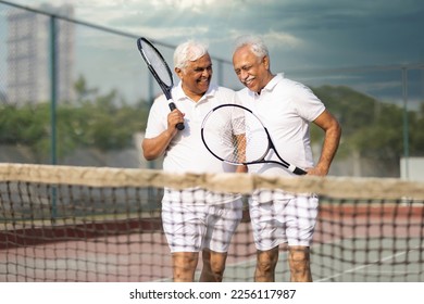 Active senior tennis players meeting at the net after a match and talking. - Powered by Shutterstock