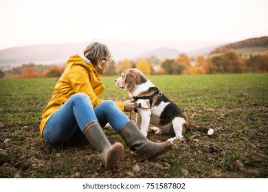 Active senior woman with dog on a walk in a beautiful autumn nature.