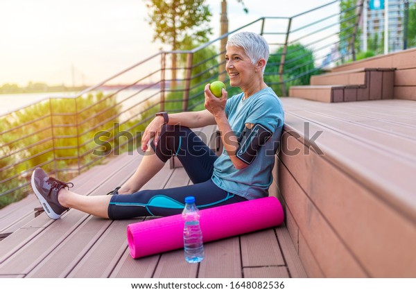 Active Senior Woman Eating Apple After Exercise Mature Woman Holding