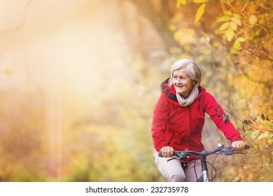 Active Senior Woman Ridding Bike In Autumn Nature.