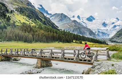 aktive ältere Frau, die ihr E-Mountainbike im Roseg-Tal unter den Gletschern und Gipfeln der Sella-Gruppe und Piz Roseg reitet