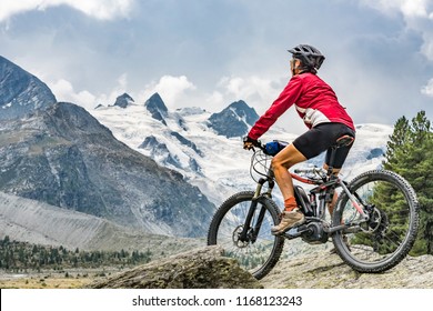 active senior woman, riding her e-mountain bike in the Roseg valley below the glaciers and summits of the Sella Group and Piz Roseg - Shutterstock ID 1168123243