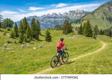active senior woman riding her electric mountain bike below the seven summits of Churfirsten in Canton St. Gallen, Switzerland