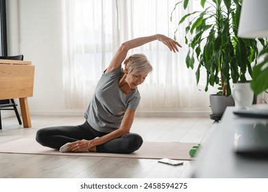 Active senior woman stretching and exercising indoors. Exercise for older adults - Powered by Shutterstock