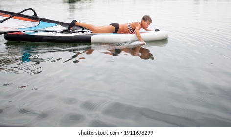 Active Senior Woman In Swim Suit Ride Lying On Windsurfing In The Water 