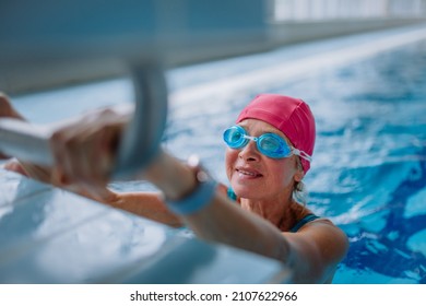 Active senior woman swimmer holding onto starting block preparing to swim in indoors swimming pool. - Powered by Shutterstock