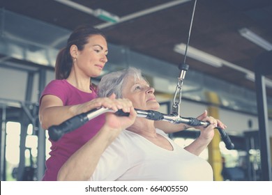 Active senior woman working exercise in the gym. Personal trainer helping senior woman. Workout in gym. - Powered by Shutterstock