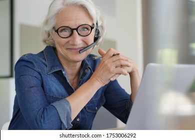 Active senior woman working from home on laptop