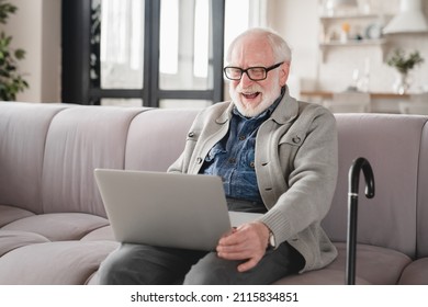 Active Seniors. Caucasian Elderly Senior Old Man Grandfather Using Laptop For Watching Movies, Online Medicine, Working Remotely, Having Videocall With Grandchildren On The Sofa In Living-room