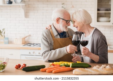 Active seniors concept. Caucasian elderly couple spouses wife and husband grandparents looking at each other, drinking wine, celebrating anniversary together, cooking romantic dinner at home kitchen - Powered by Shutterstock