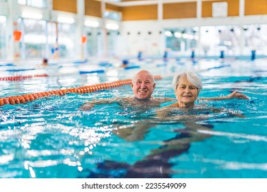 Active seniors concept. Happy elderly caucasian heterosexual married couple swimming in a pool breaststroke style. Leisure time activities for people of all ages. High quality photo - Powered by Shutterstock