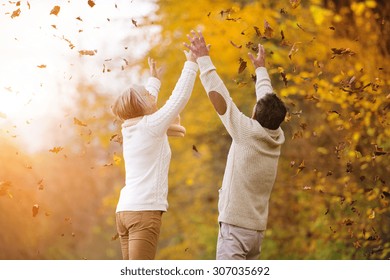 Active Seniors Having Fun And Playing With The Leaves In Autumn Forest