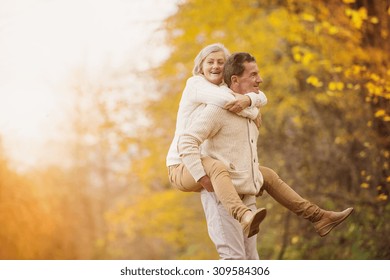 Active Seniors Having Fun And Playing With The Leaves In Autumn Forest