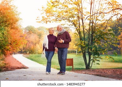 Active Seniors On A Walk In Autumn Forest