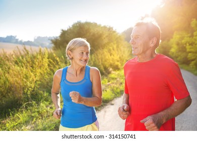 Active Seniors Running Outside In Green Nature