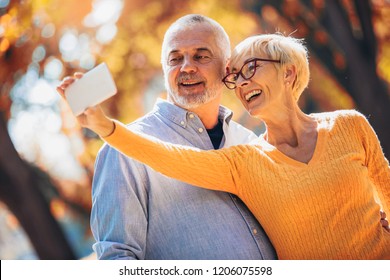 Active seniors taking selfies of them having fun outside in the autumn forest - Powered by Shutterstock