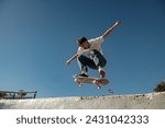 Active skateboarder jumping and performing a trick in the air in ramp of a skate park