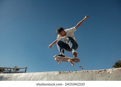 Active skateboarder jumping and performing a trick in the air in ramp of a skate park - Powered by Shutterstock