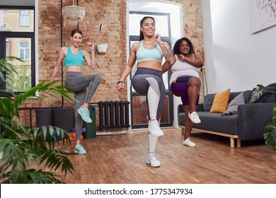 Active smiling females of different races exercising at home together making steps on place and rising their knees high