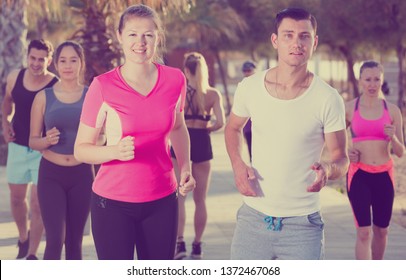 Active smiling people during running training in daytime - Shutterstock ID 1372467068