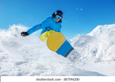 Active snowboarder jumping in winter mountains
