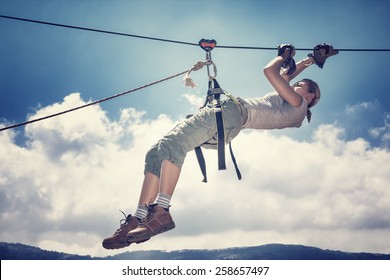 Active sportive woman hanging on the tightrope between mountains, playing rappel sport, extreme lifestyle, great sportive achievement - Powered by Shutterstock